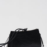 Black crossbody bag with a textured pattern on a white background