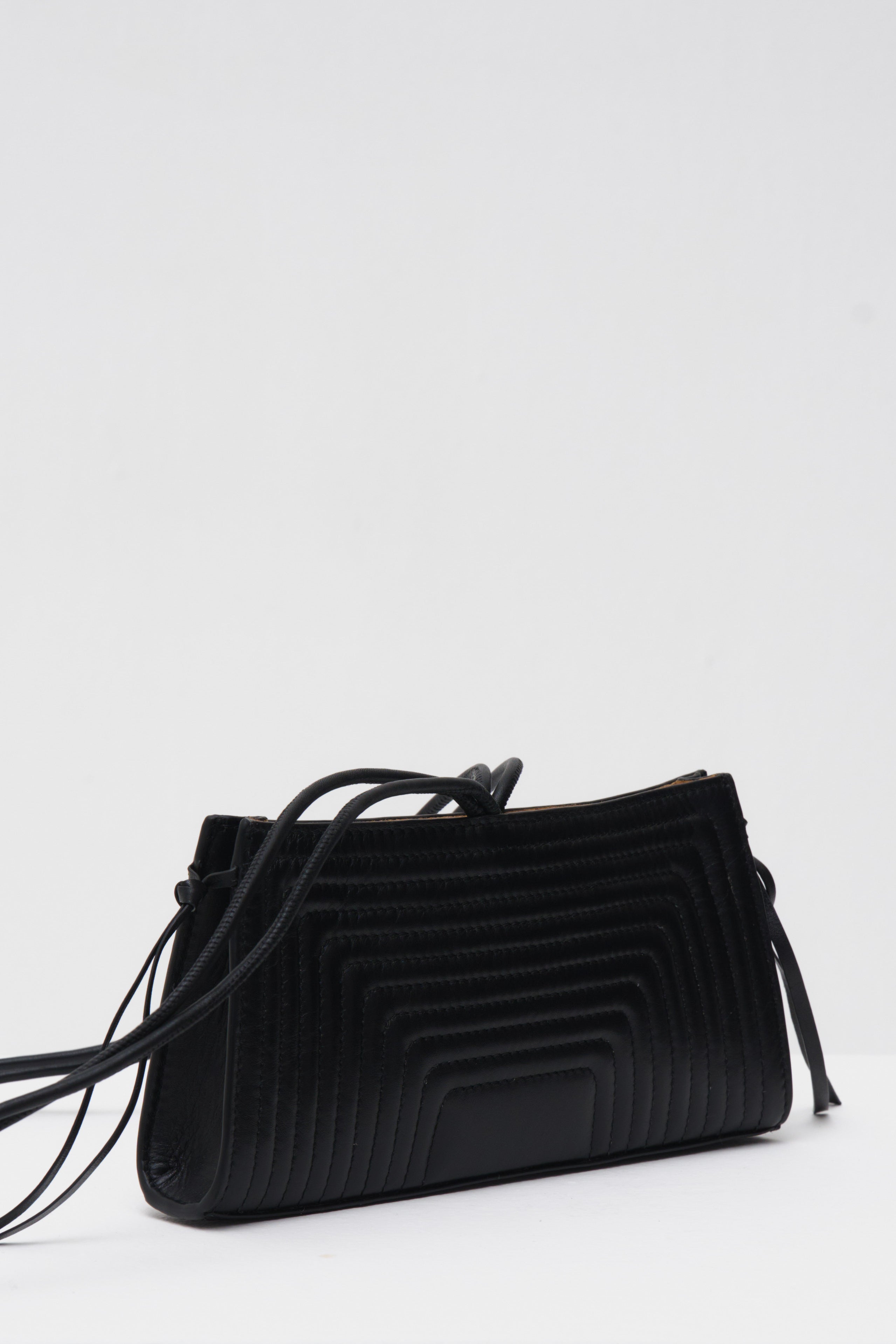 Black crossbody bag with a textured pattern on a white background