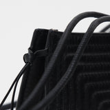 Close-up of a black textured bag with a drawstring on a light gray background