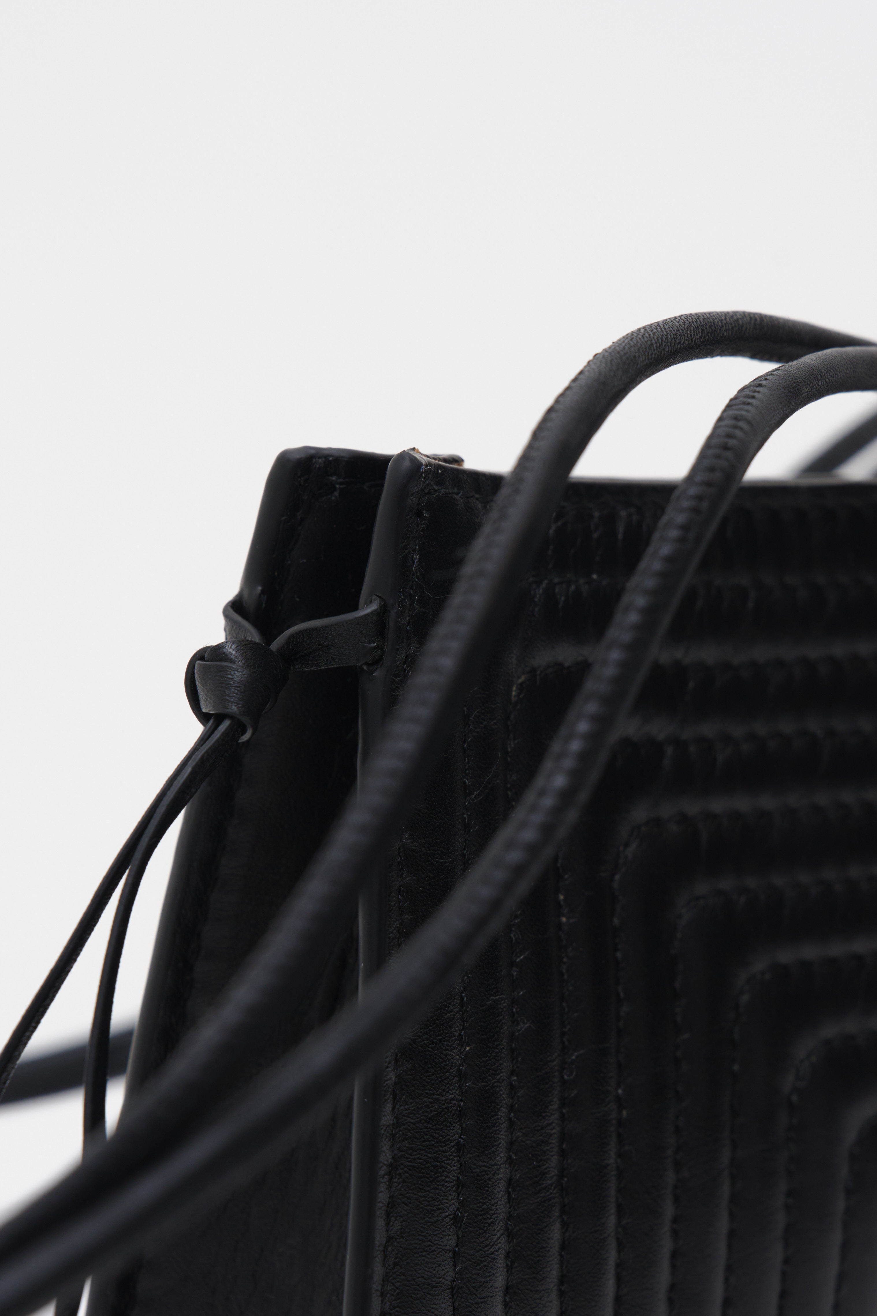Close-up of a black textured bag with a drawstring on a light gray background