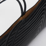 Close-up of a black textured crossbody bag on a light gray background