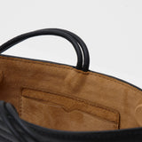 Close up of a black crossbody bag against a white background 