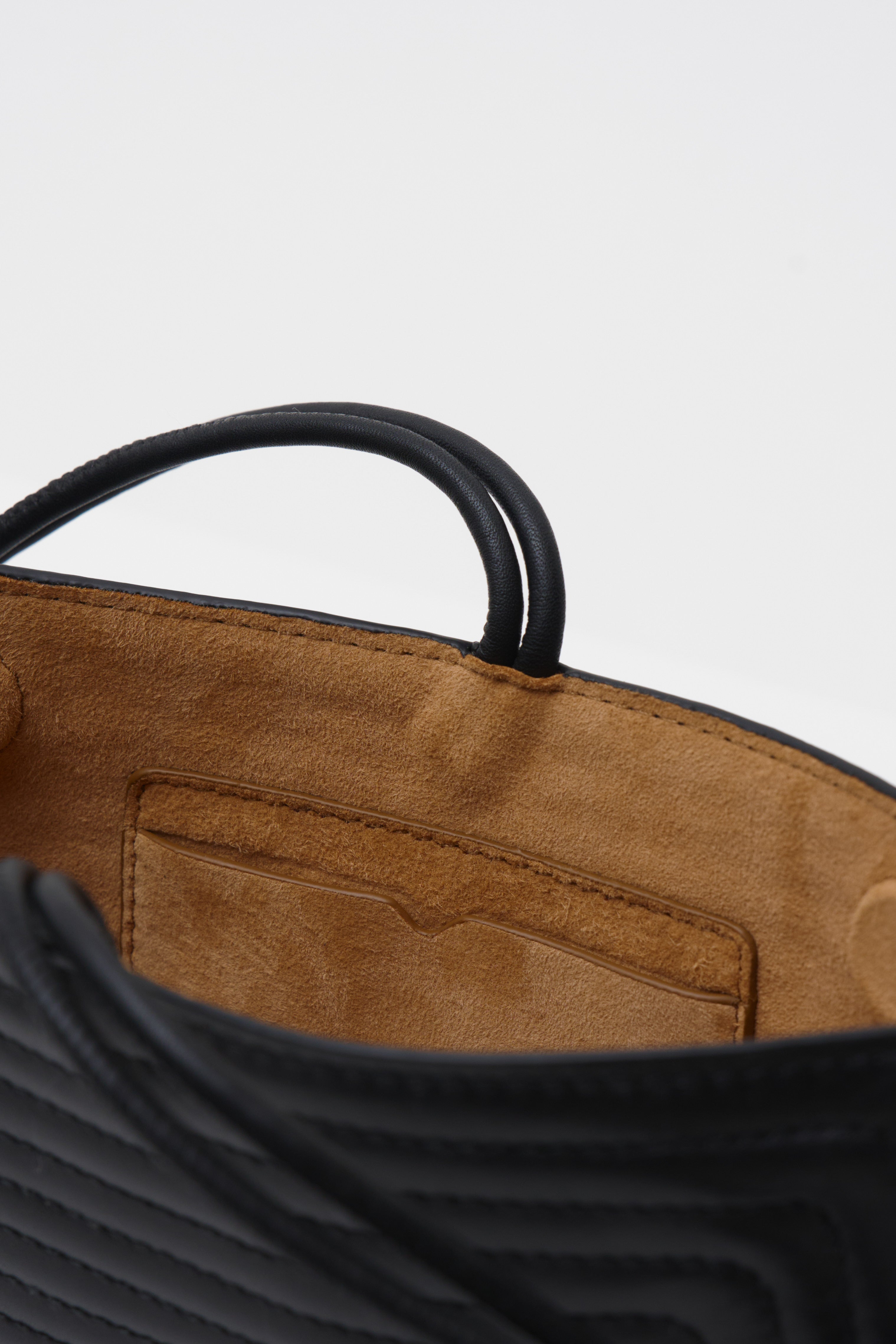 Close up of a black crossbody bag against a white background 