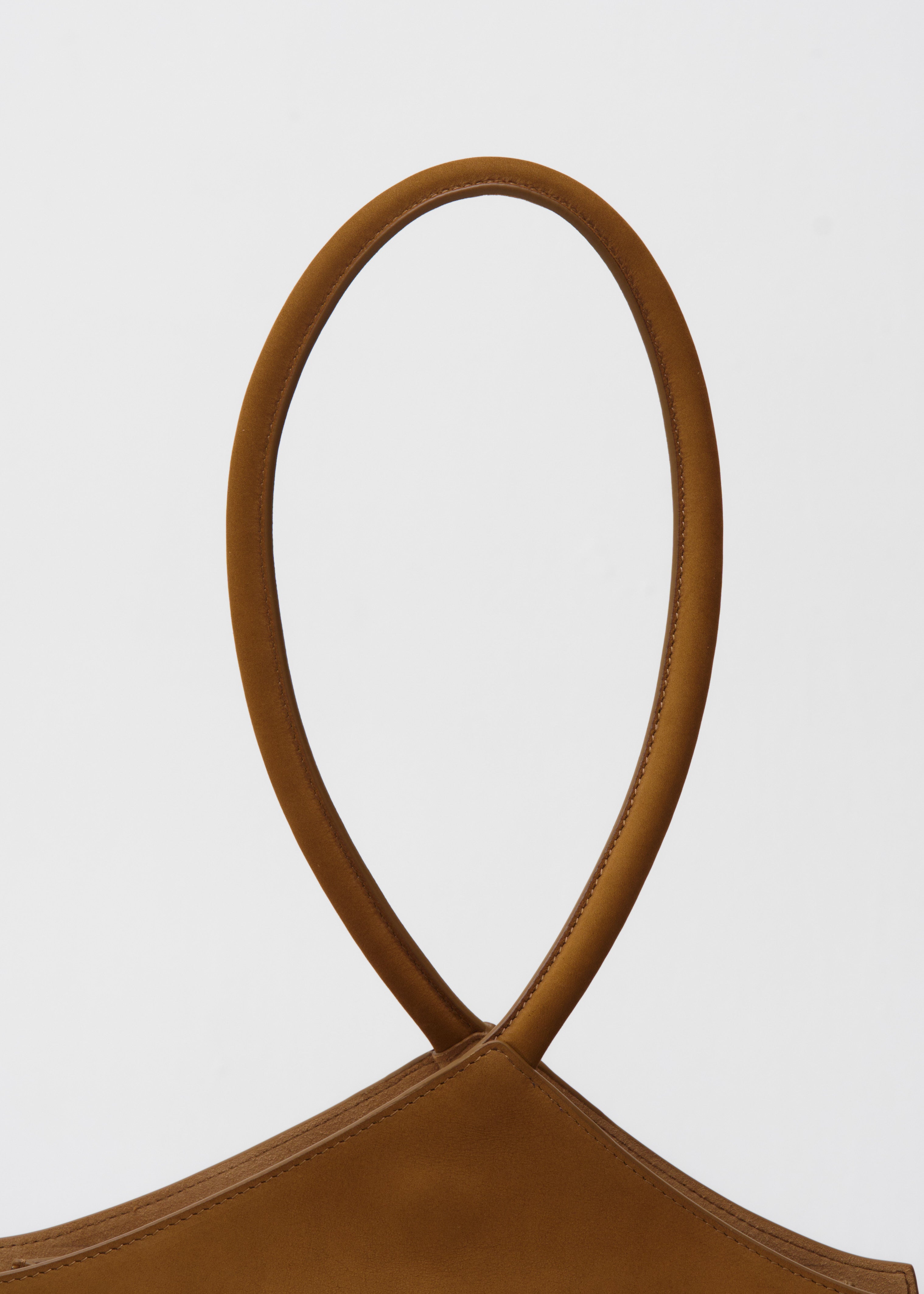 Close-up of a brown suede handbag with a rope handle on a white background