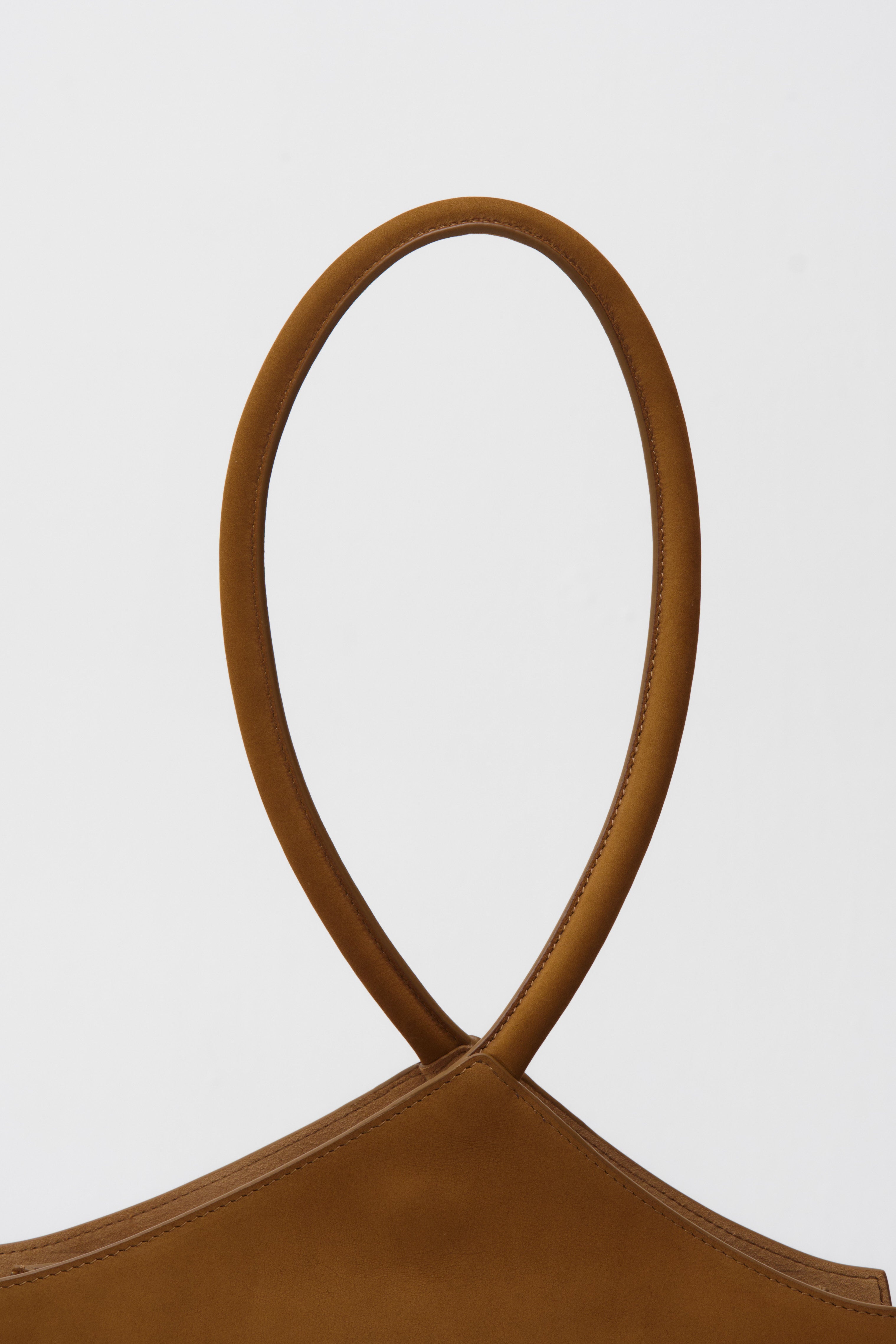 Close-up of a brown suede handbag with a rope handle on a white background