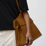 Person holding a brown leather bag against a white background