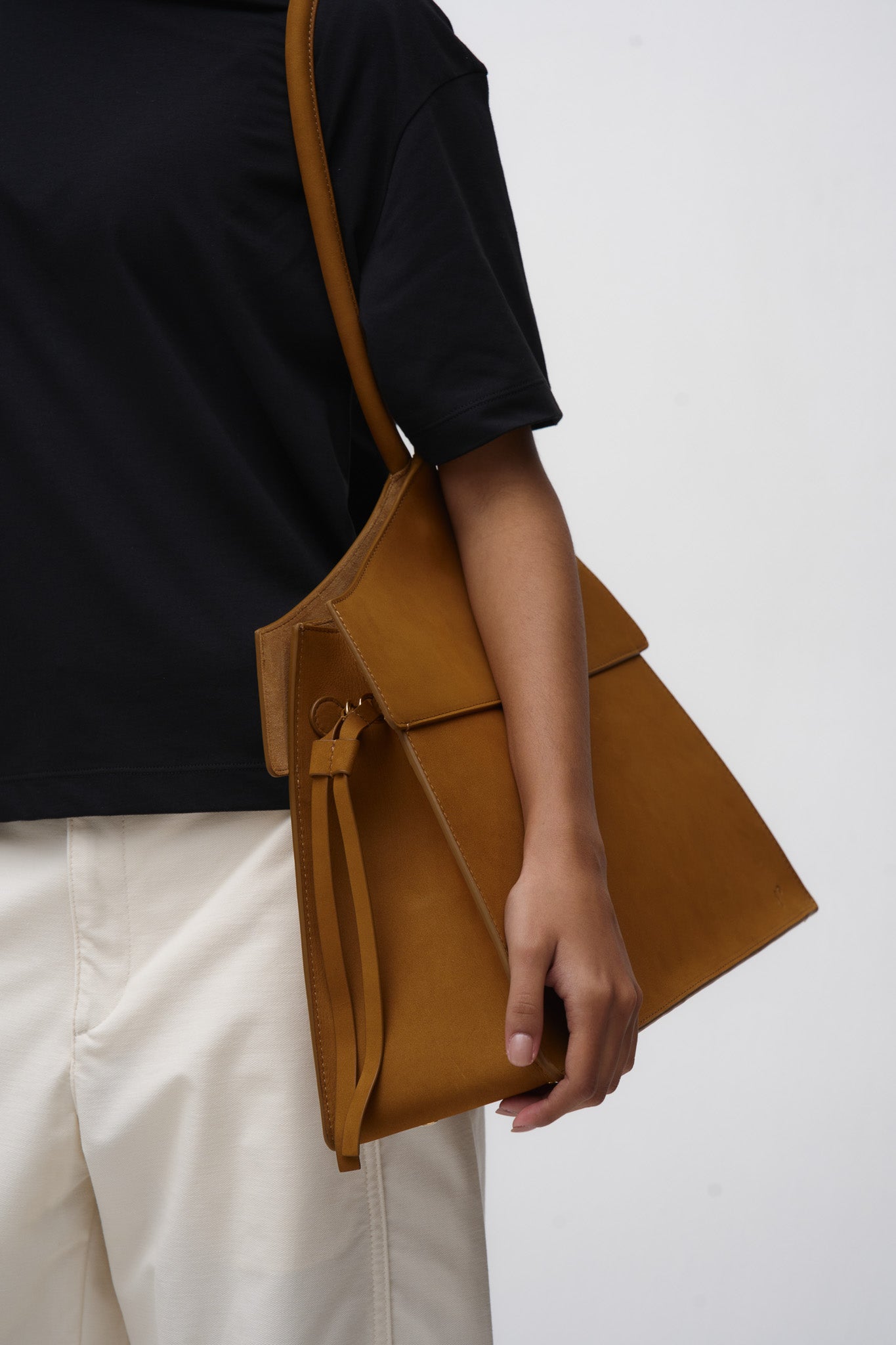 Person holding a brown leather bag against a white background