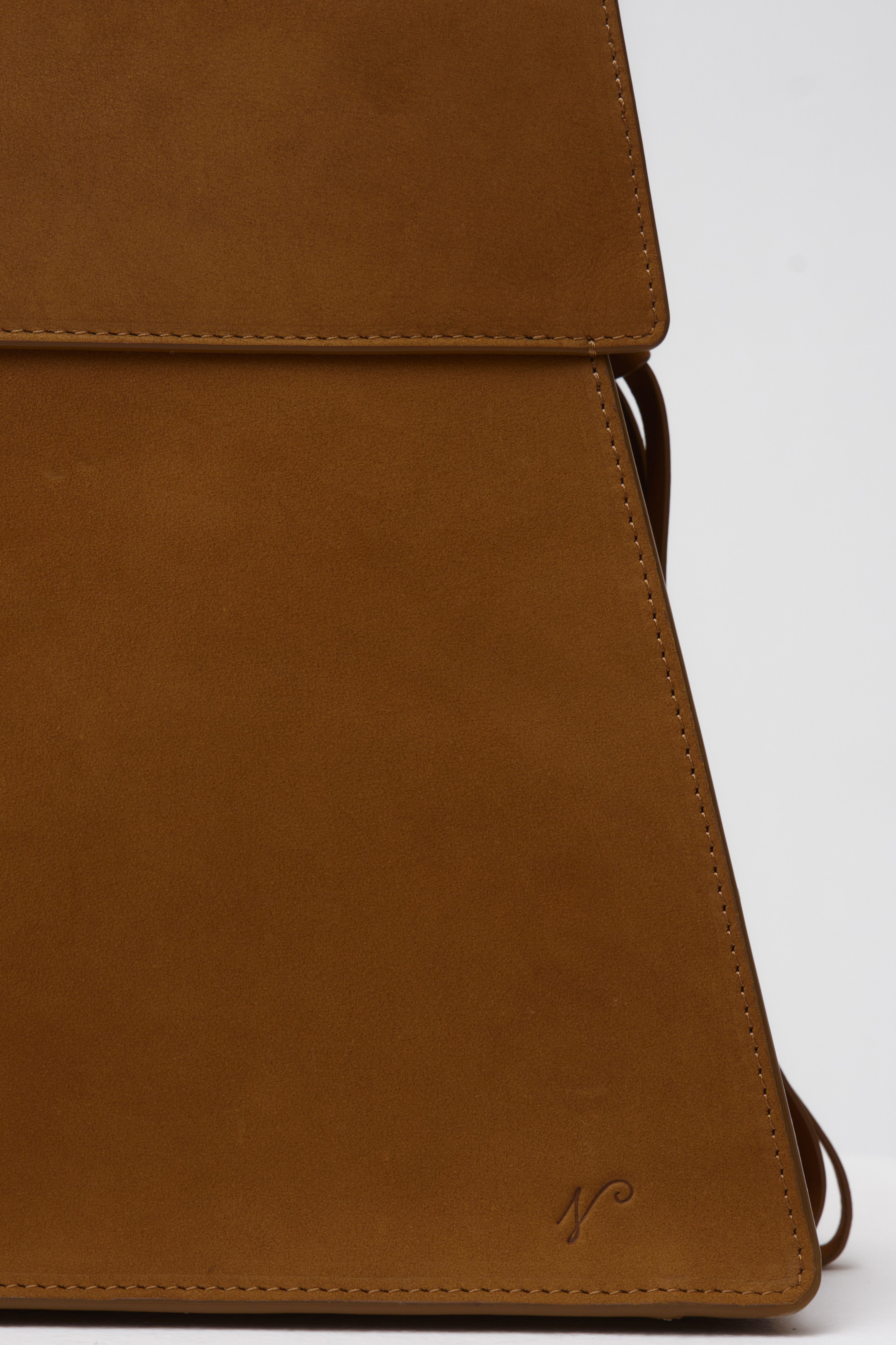 Close-up of a brown suede bag with a visible brand logo on a white background