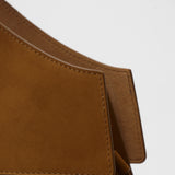 Close-up of a brown suede bag with a white background