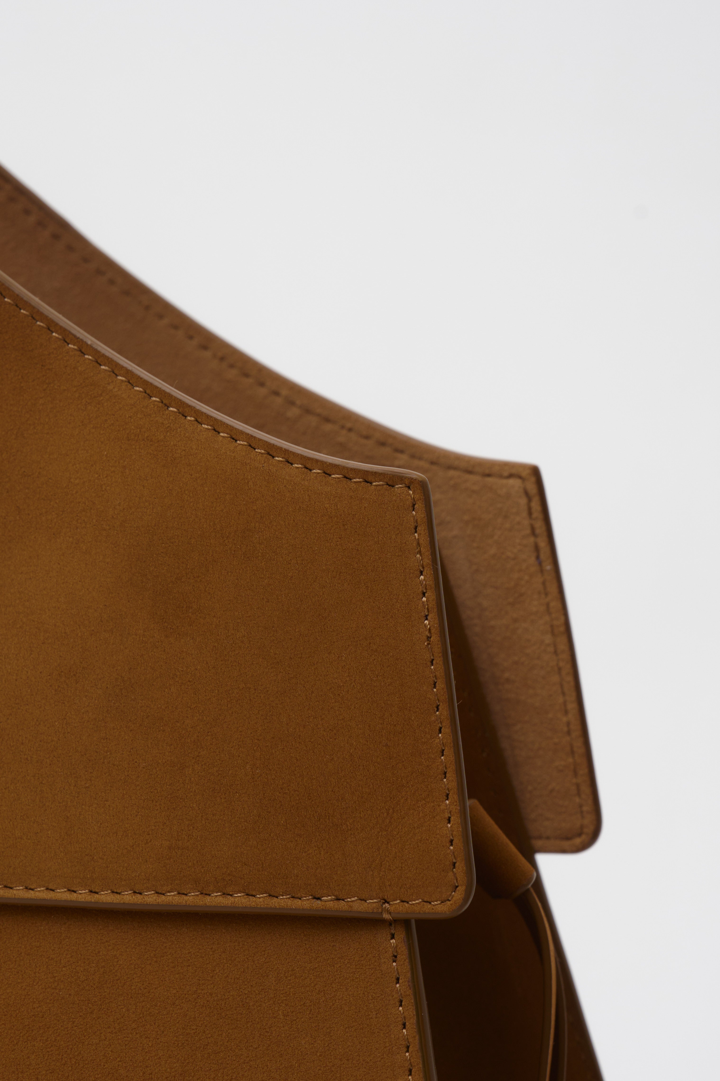 Close-up of a brown suede bag with a white background