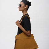 Woman holding a brown suede tote bag against a white background