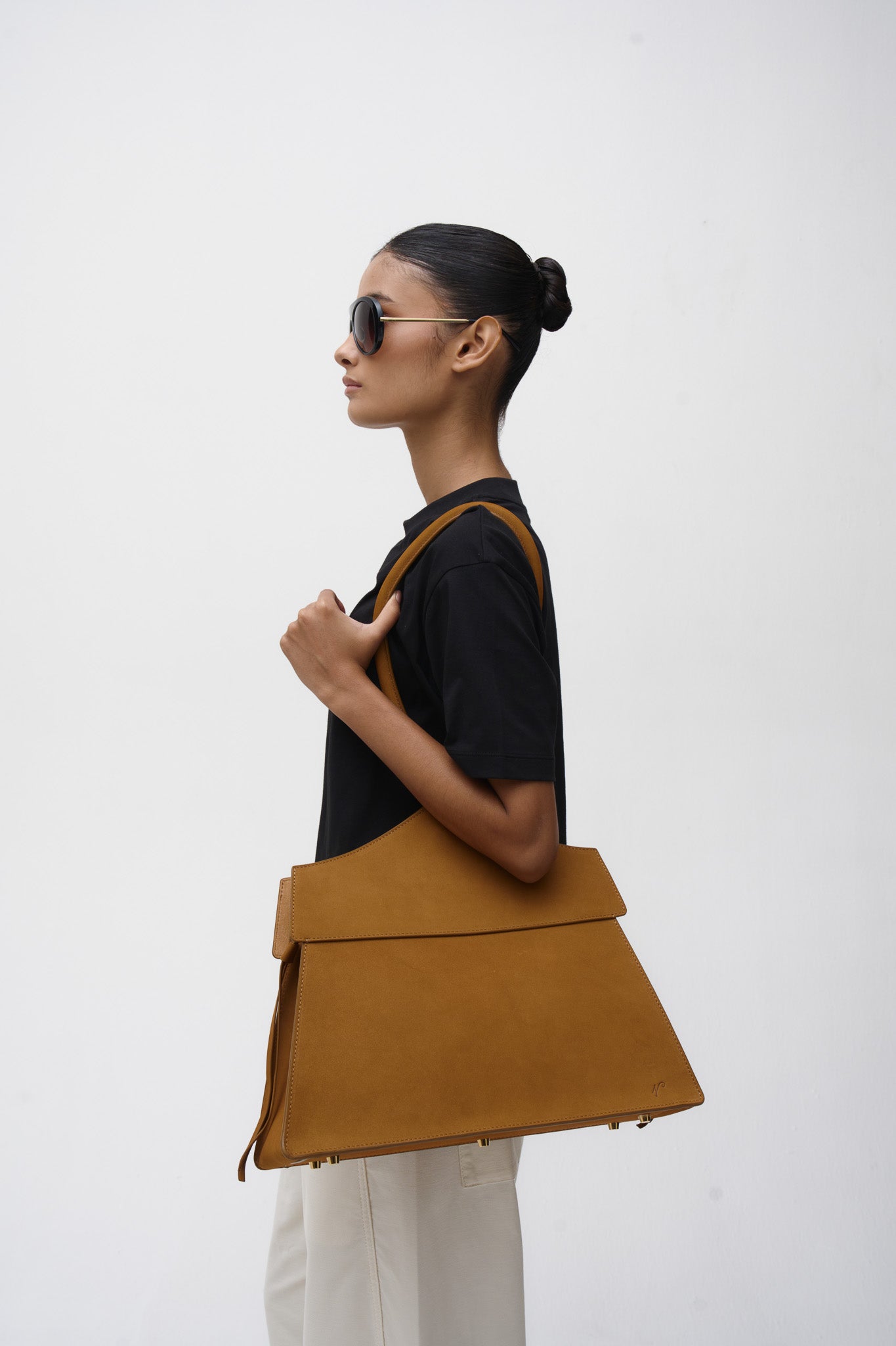 Woman holding a brown suede tote bag against a white background