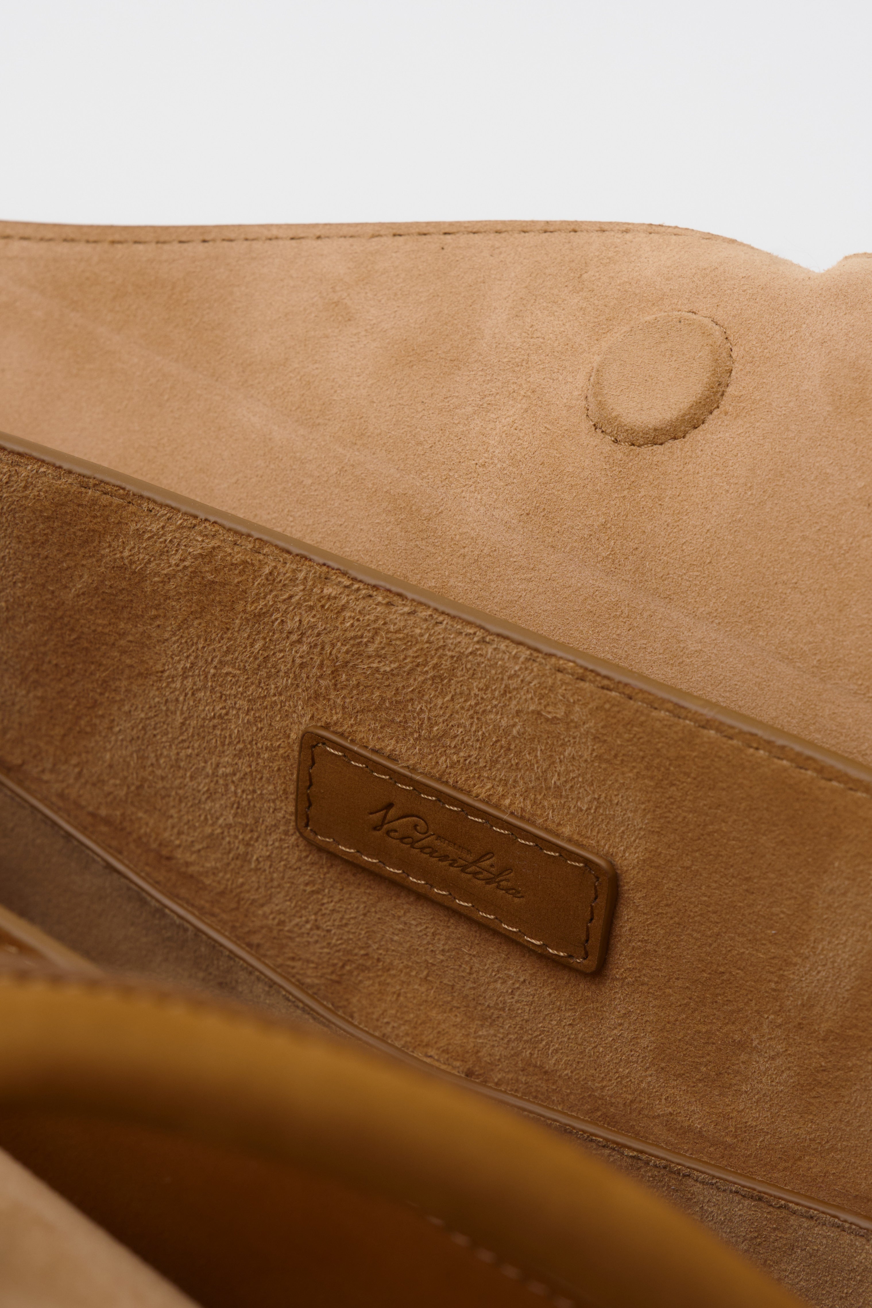 Close-up of a brown suede bag with a visible brand label.