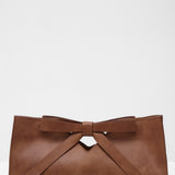 Brown leather clutch bag with a bow on a white background