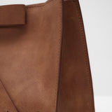 Brown leather handbag with a bow on a white background