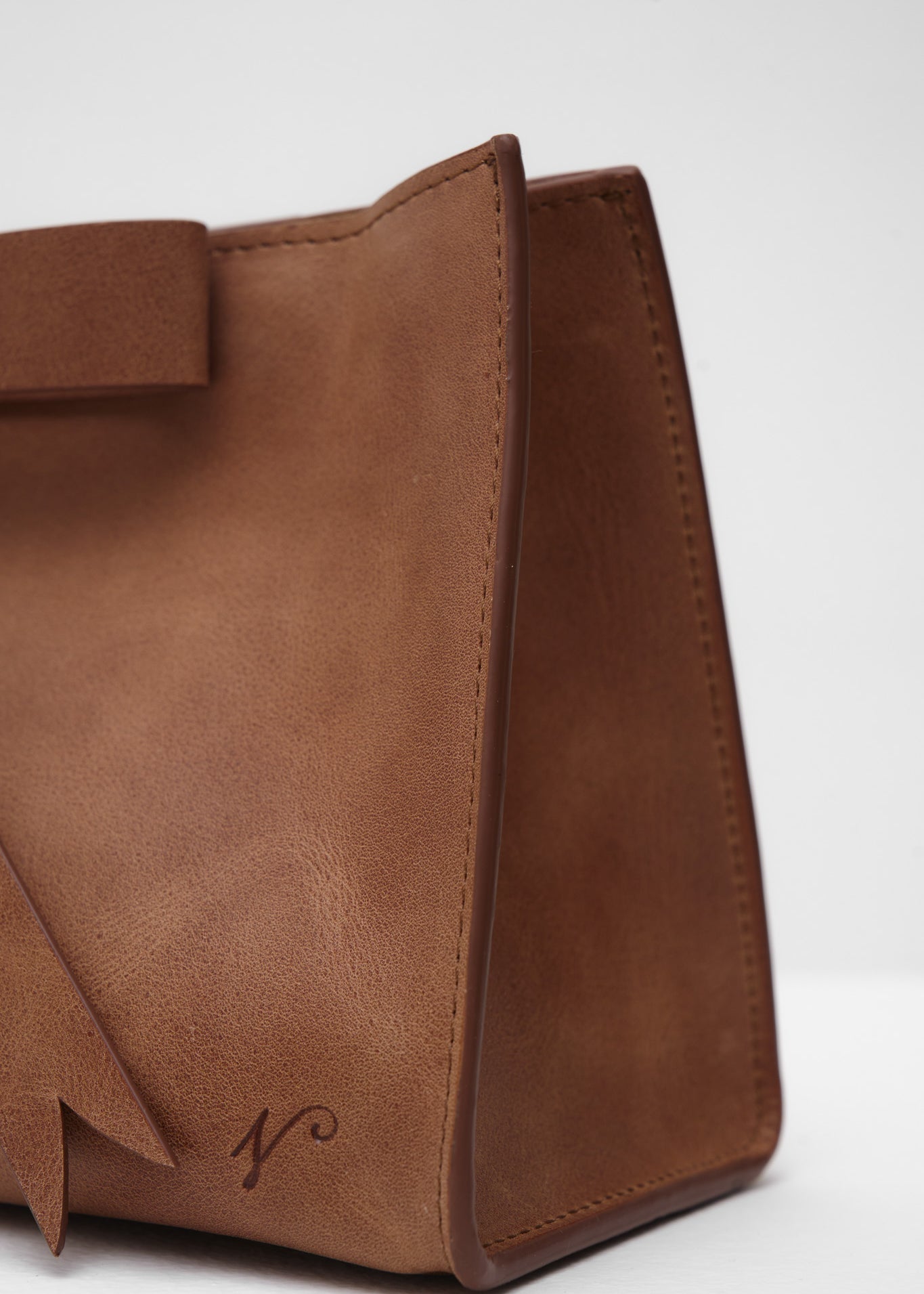 Brown leather handbag with a bow on a white background