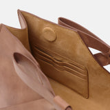 Close-up of a brown leather handbag with a white background