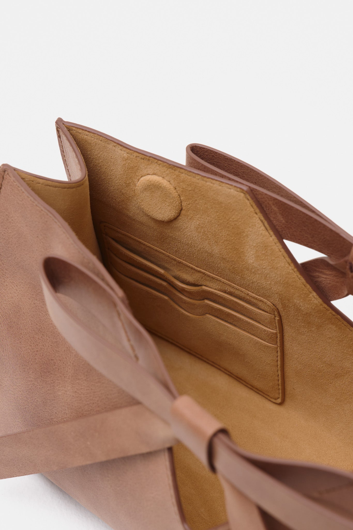 Close-up of a brown leather handbag with a white background
