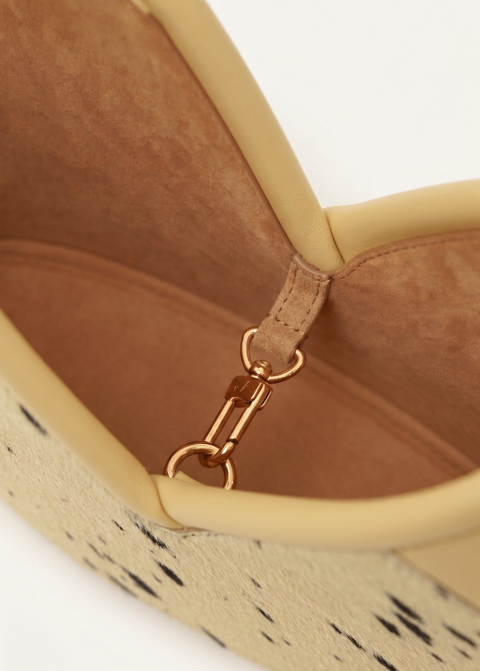 Close up of a hair-on leather handbag against a white background