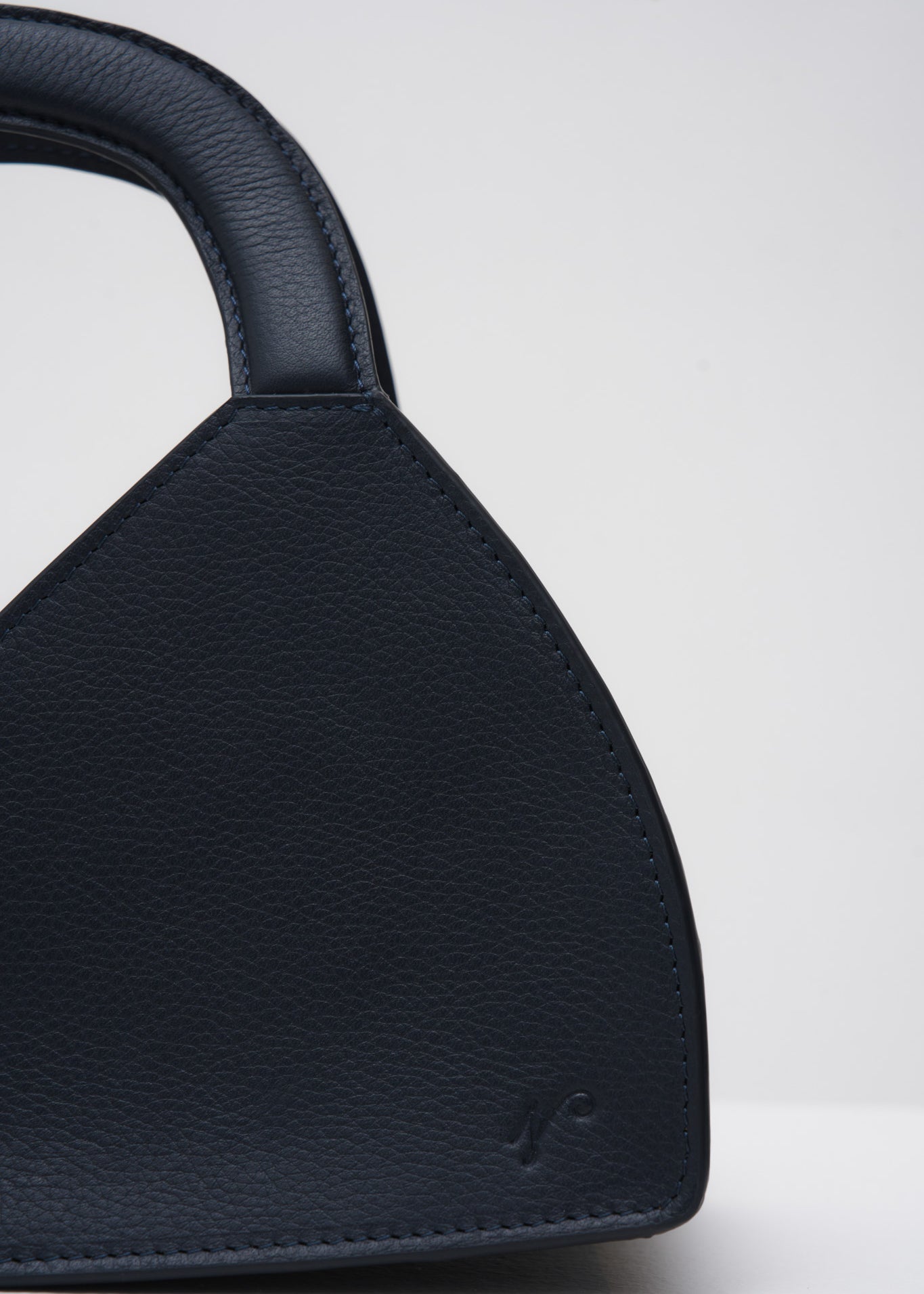 Navy blue handbag with a structured handle on a white background