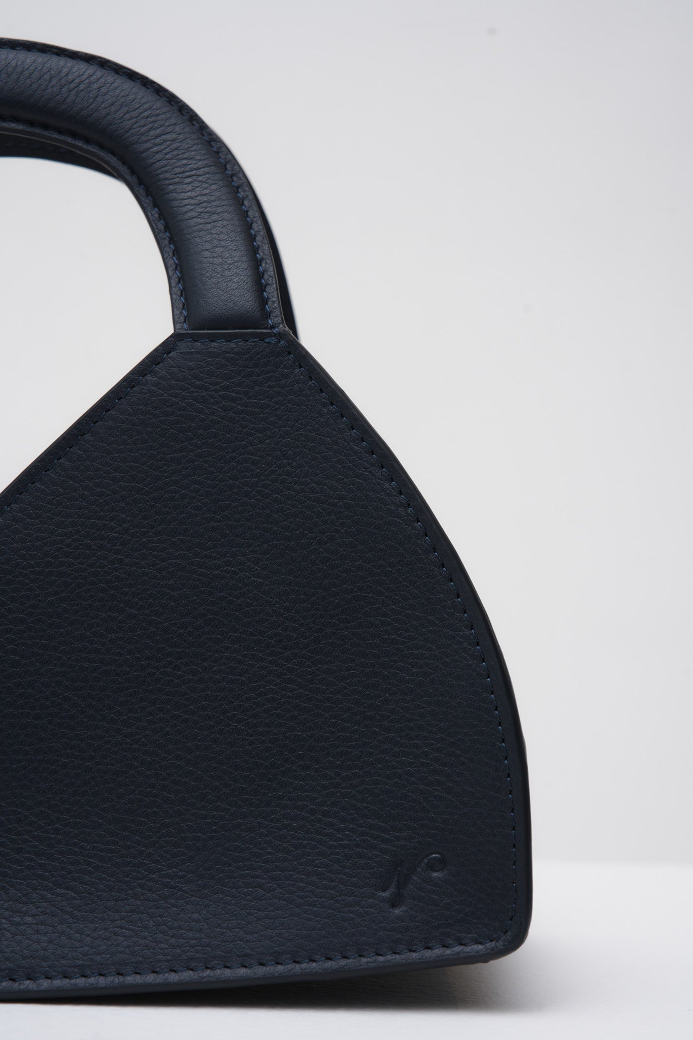 Navy blue handbag with a structured handle on a white background