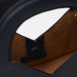 Close up of a navy blue structured handbag against a white background