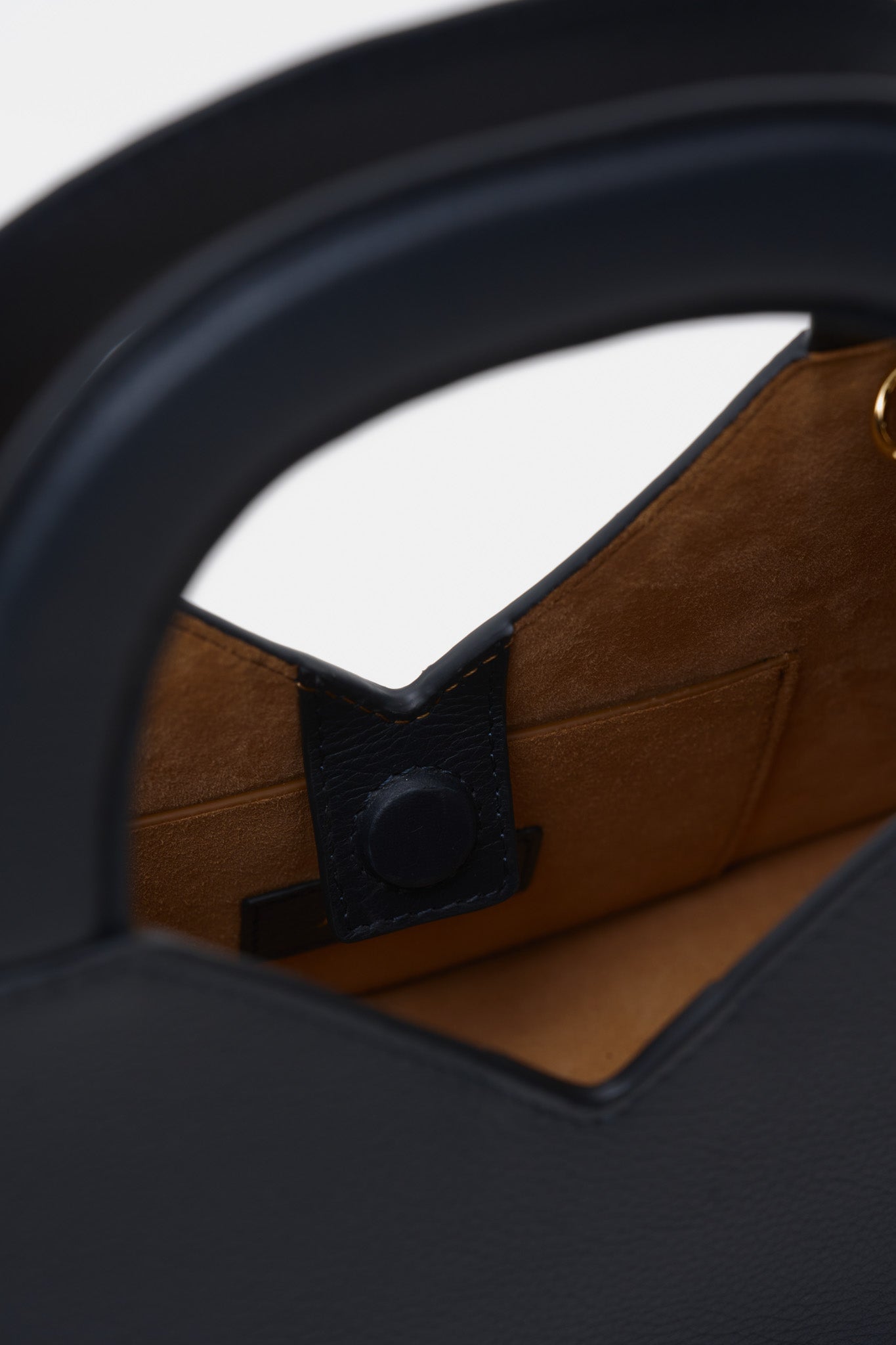 Close up of a navy blue structured handbag against a white background