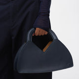 Person holding a navy blue handbag against a white background
