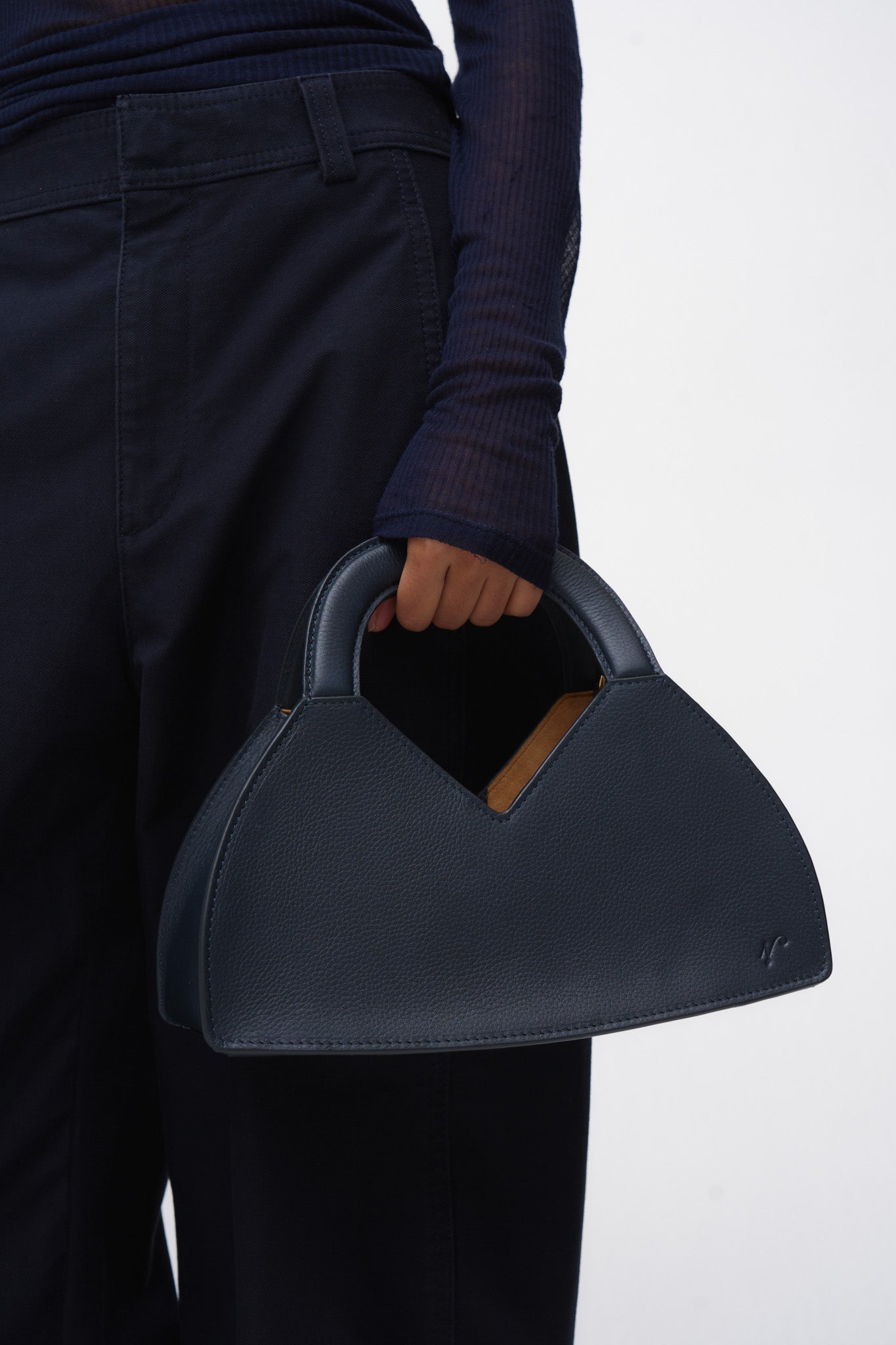 Person holding a navy blue handbag against a white background