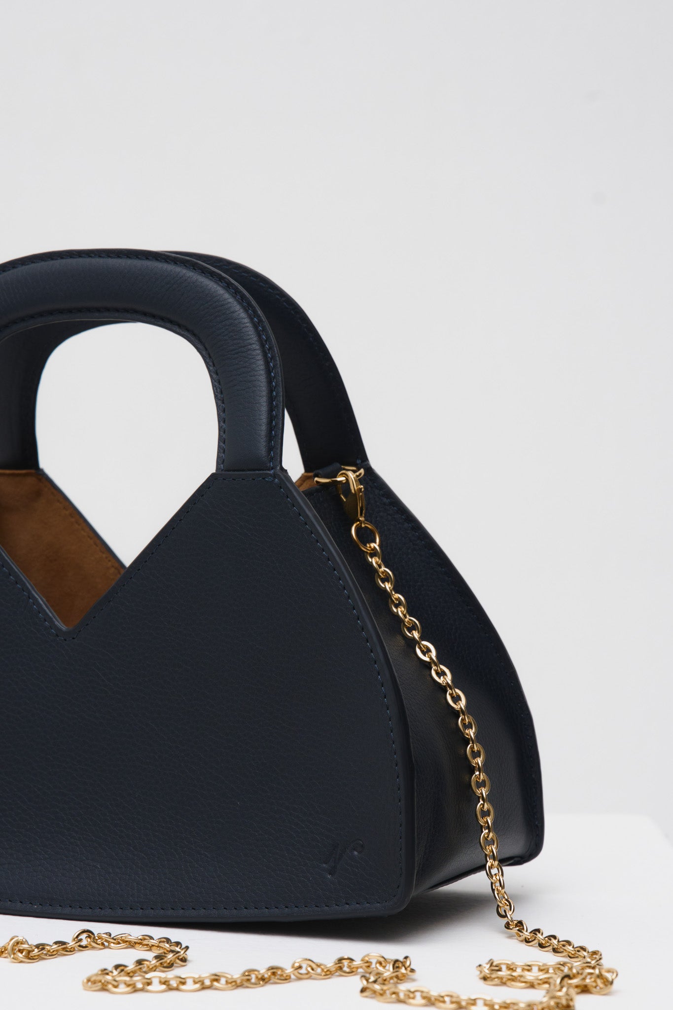 Navy blue handbag with gold chain on a white background