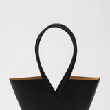Black leather handbag with unique handle design on a white background