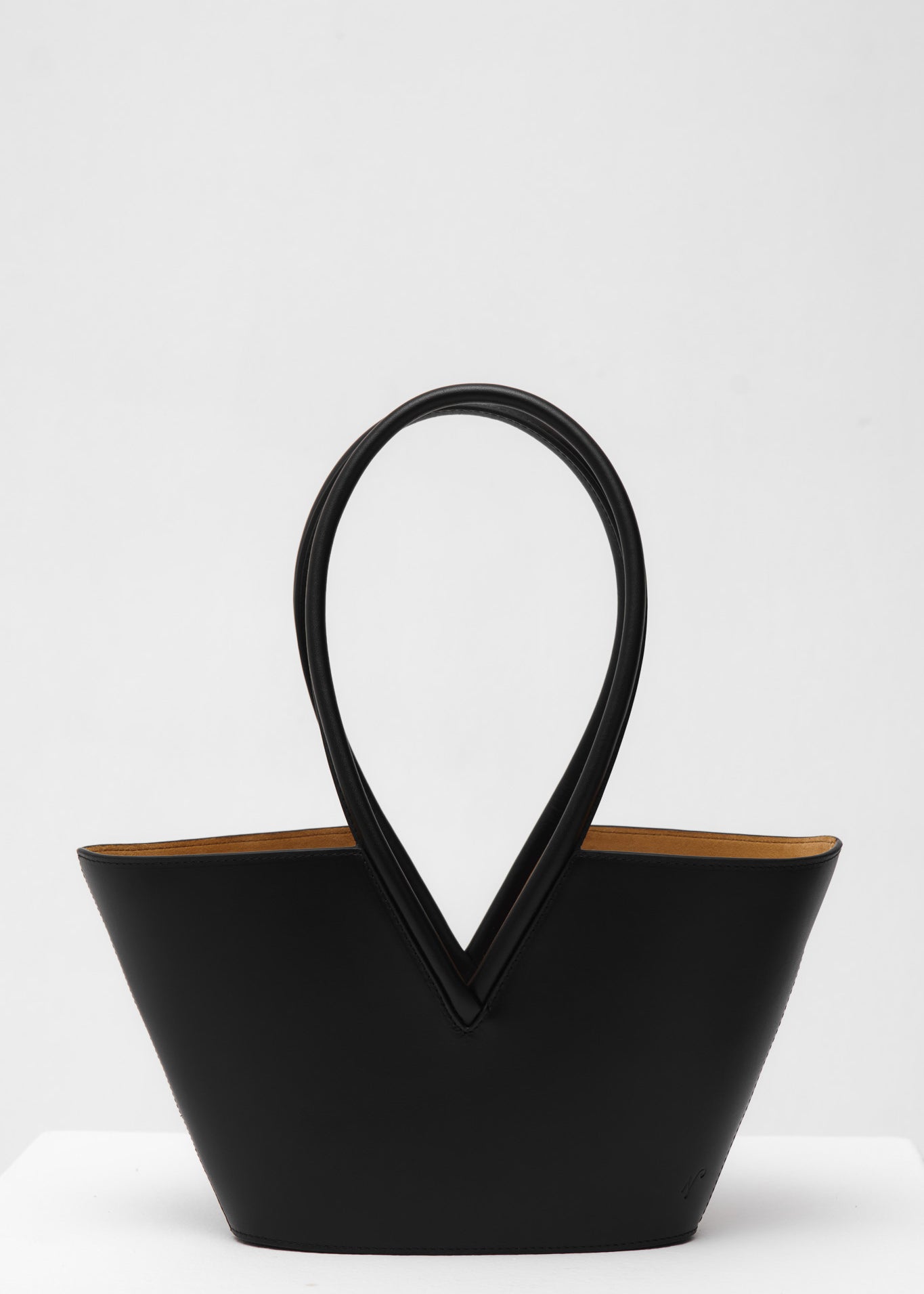 Black leather handbag with unique handle design on a white background