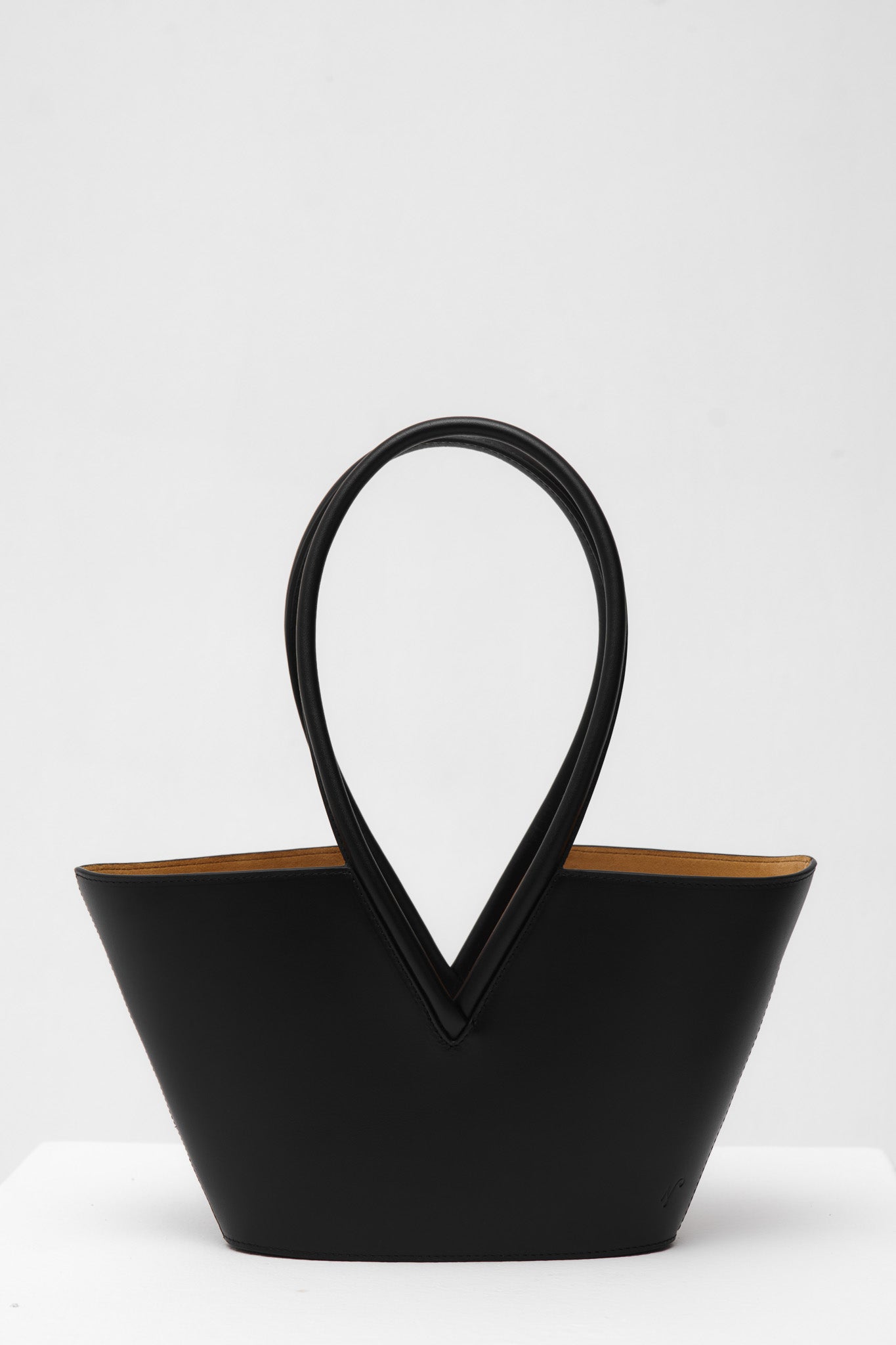 Black leather handbag with unique handle design on a white background