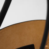 Close up of a black leather handbag with a visible brand logo on a white background