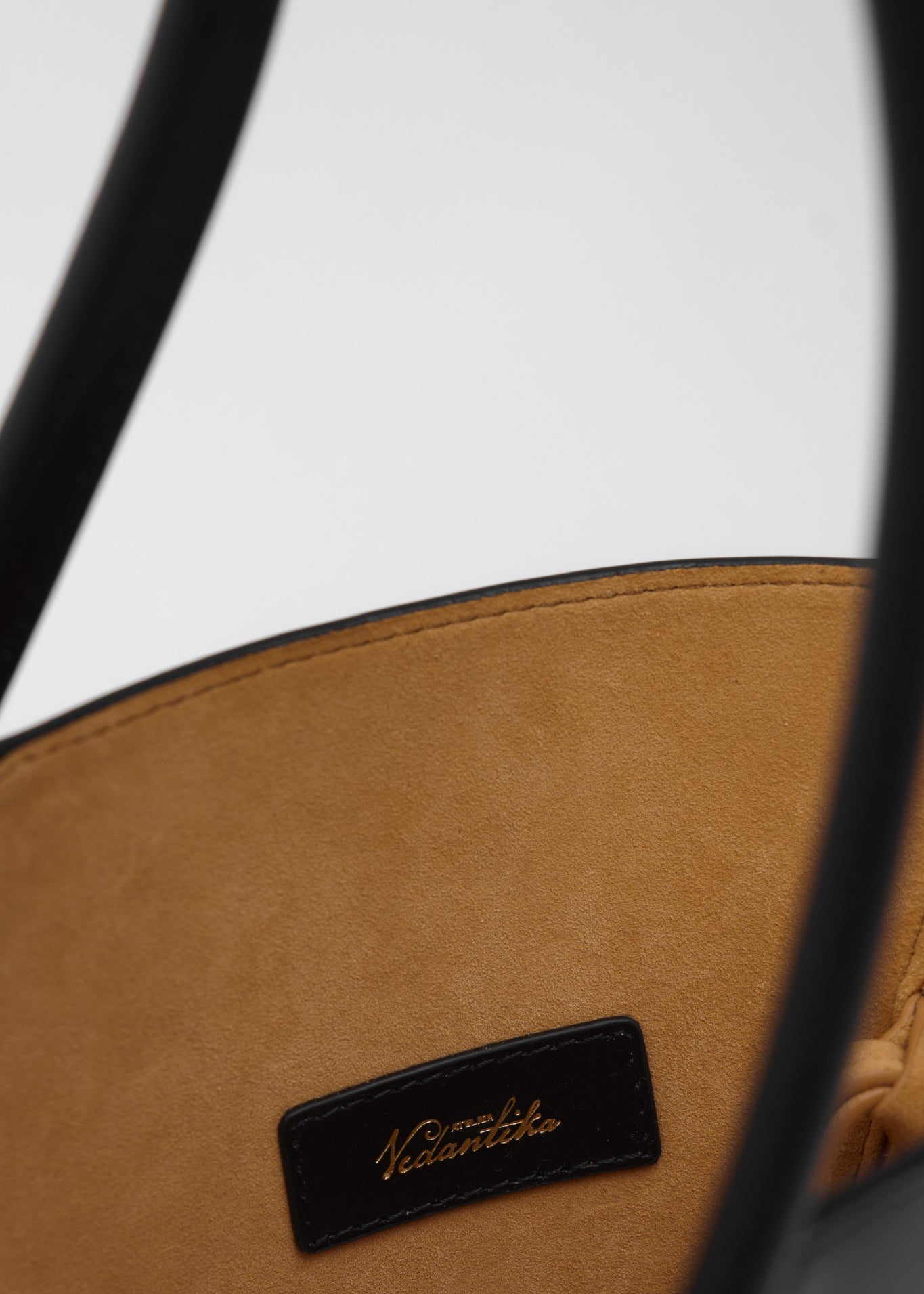 Close up of a black leather handbag with a visible brand logo on a white background