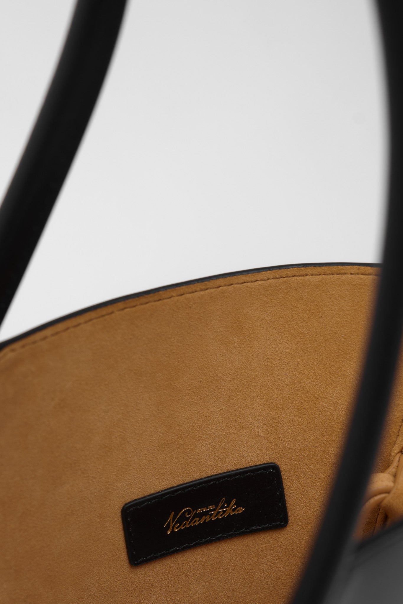 Close up of a black leather handbag with a visible brand logo on a white background