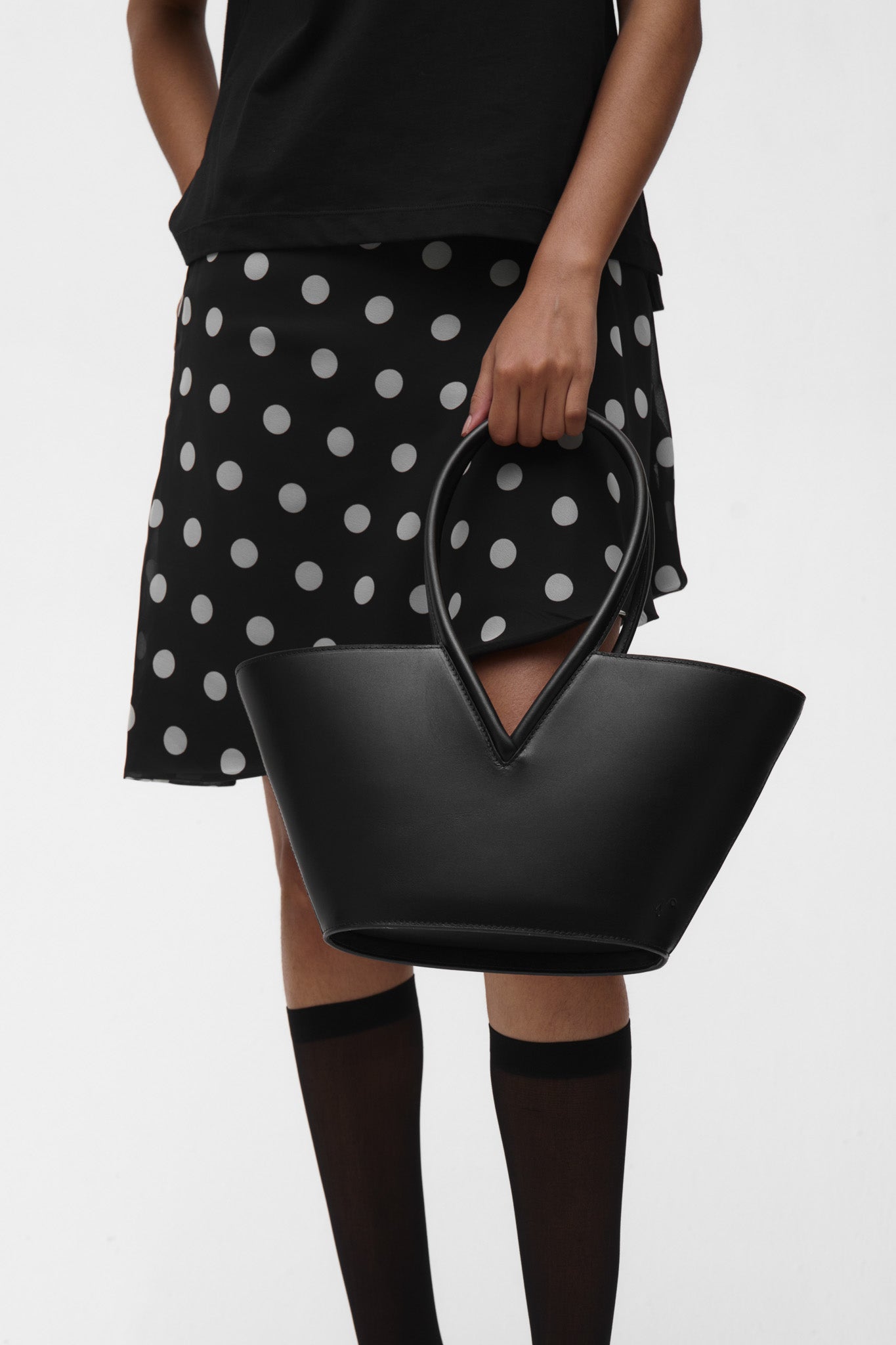 Woman wearing holding a black structured leather handbag on a white background
