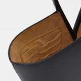 Close-up of a black leather handbag with brown suede interior on a white background