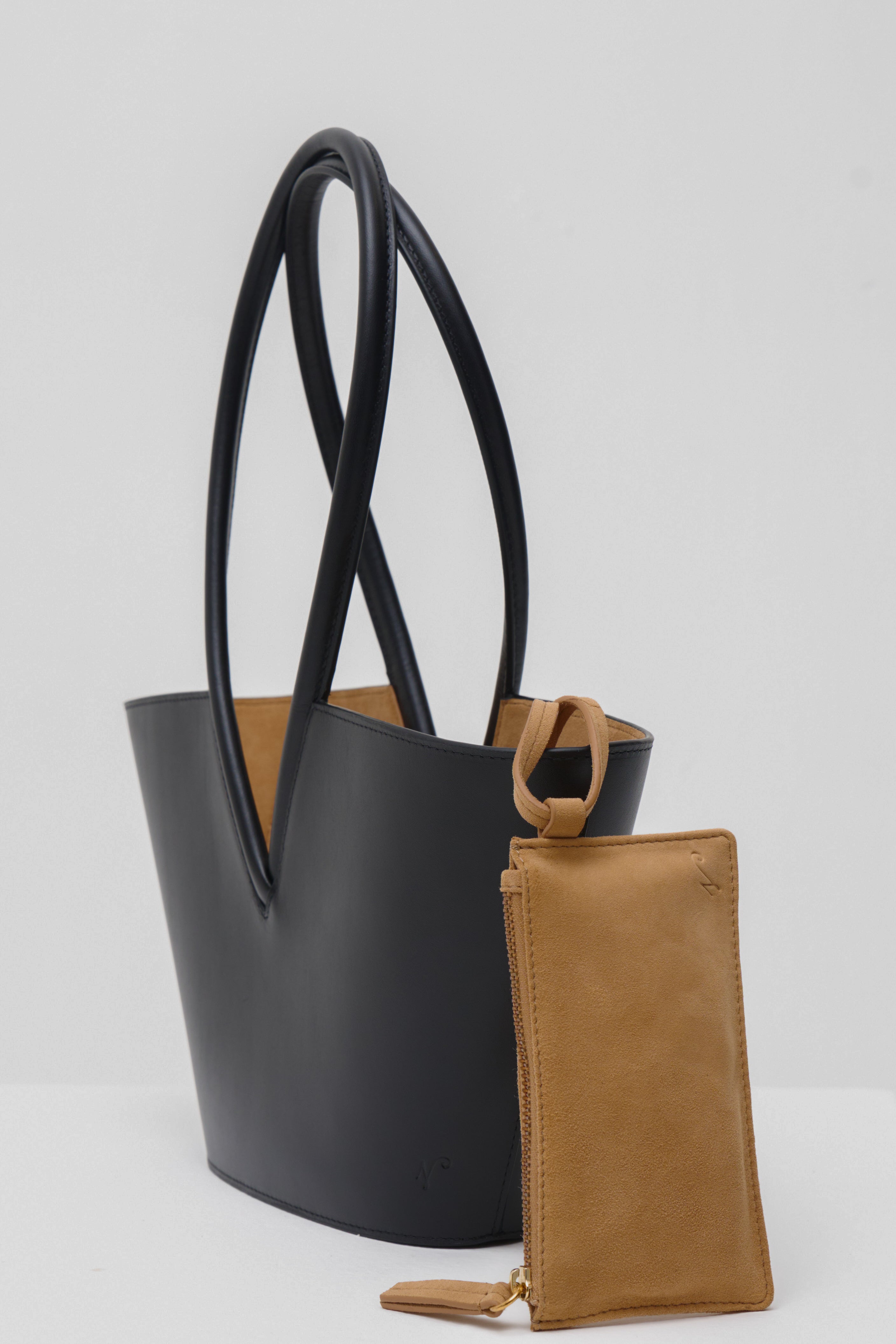 Black leather shoulder bag with a matching brown pouch on a white background