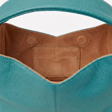 Close-up of a teal handbag with brown interior on a white background