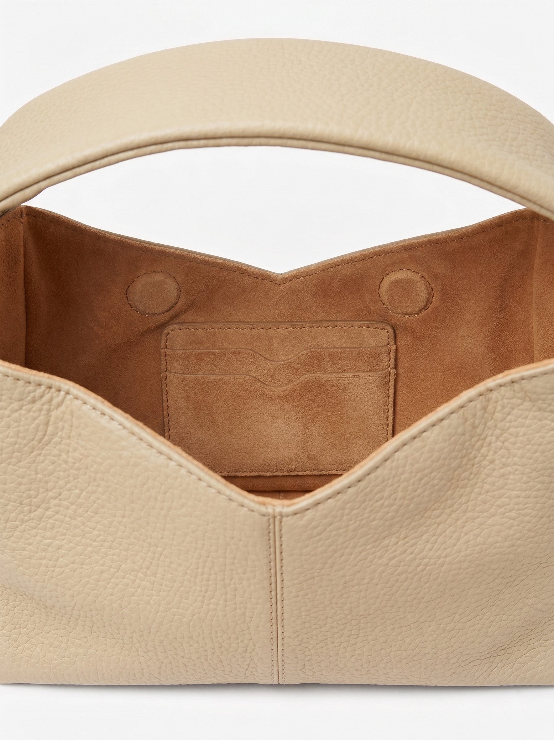 Close-up of a beige leather handbag with a white background